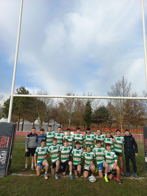 Équipe de rugby masculin du lycée agricole de Beaulieu Lavacant devant les buts avec leur entraîneur. Maillots rayés vert et blanc. Une première ligne est avec un genou à terre et une deuxième ligne debout derrière. Temps ensoleillé.